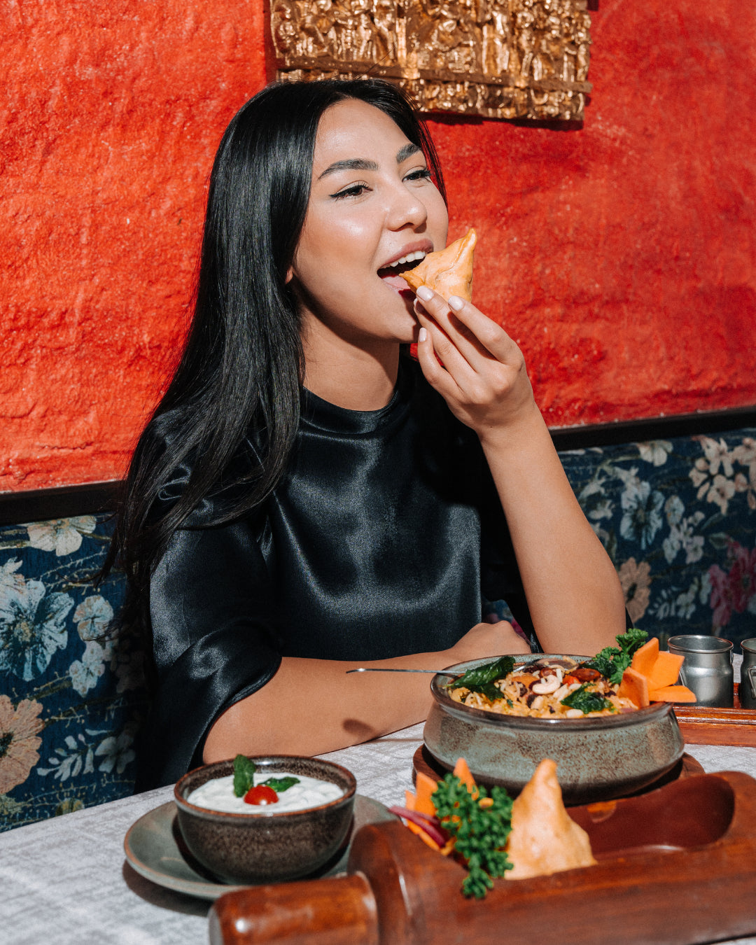 Guest with samosa at the red wall